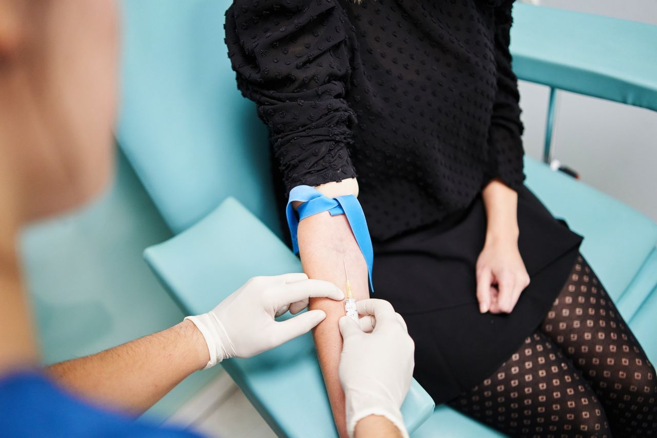 Healthcare professional drawing blood from a patient’s arm in clinic