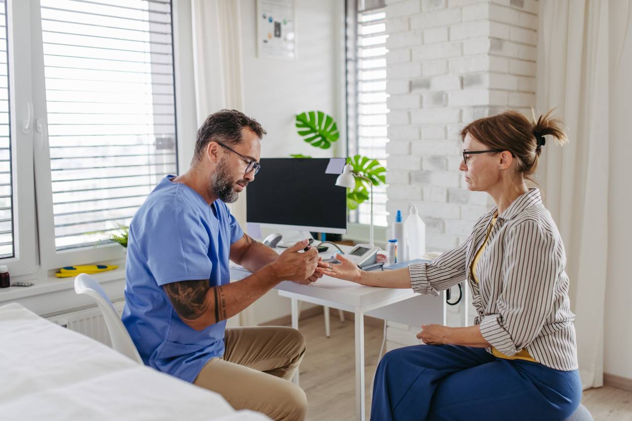 Doctor checking a patient’s blood sugar level during a medical appointment