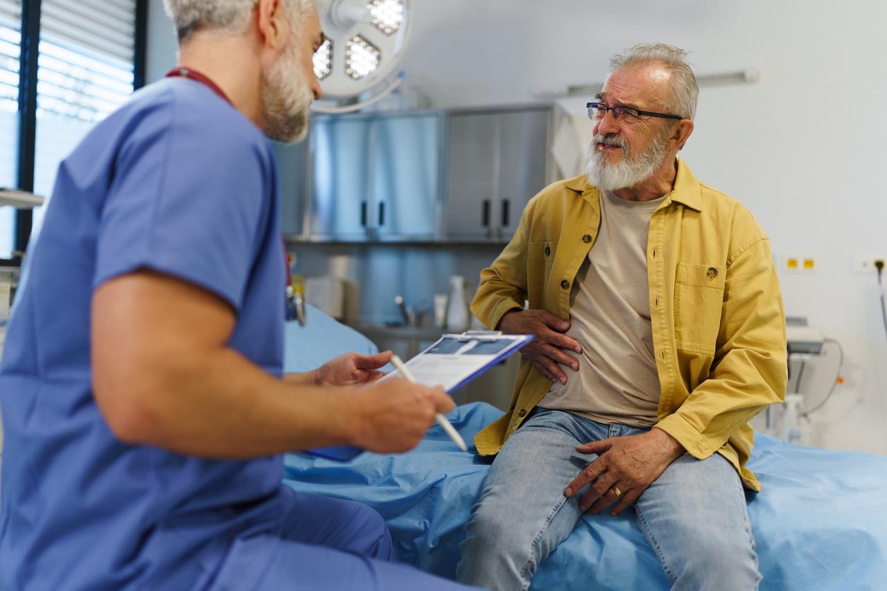 Senior man with stomach pain talks to doctor