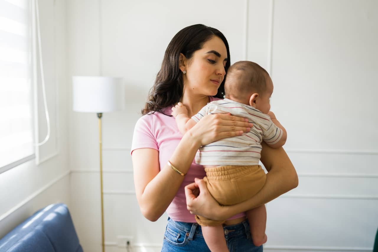 A young woman burping a newborn