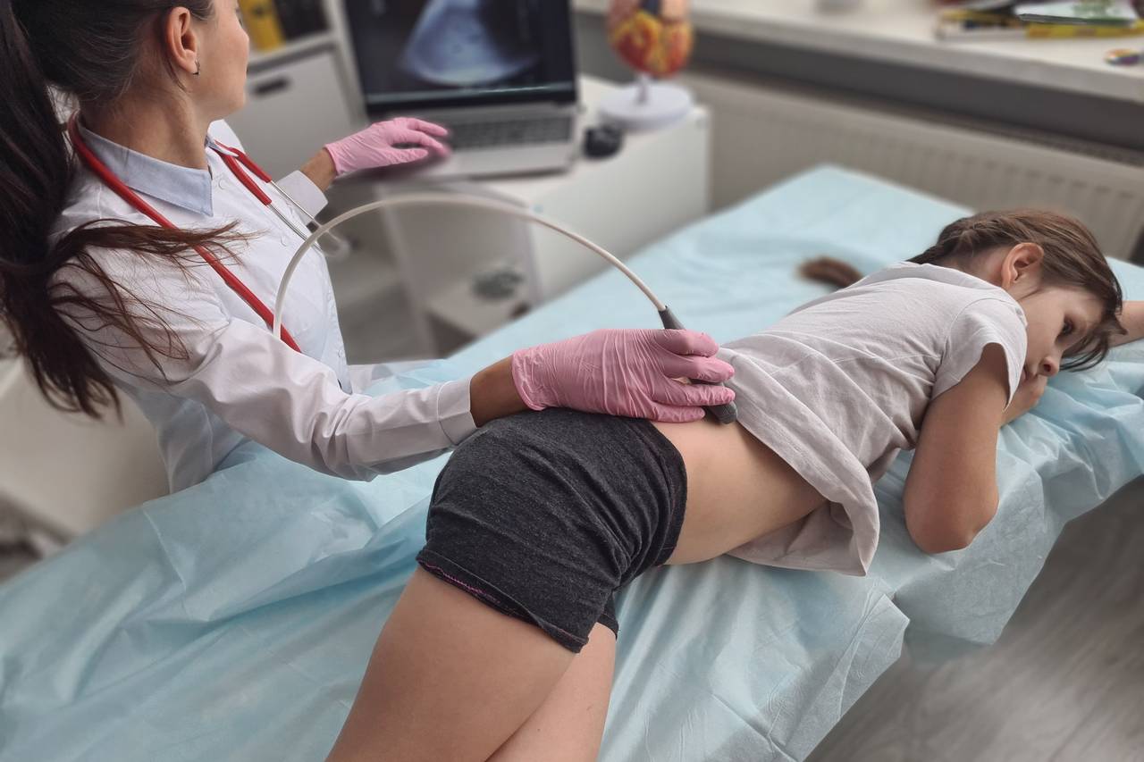 Doctor performs abdominal ultrasound on young girl