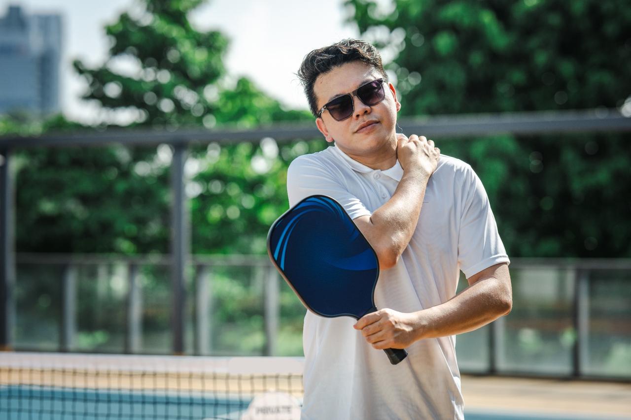 Man holding pickleball paddle and neck