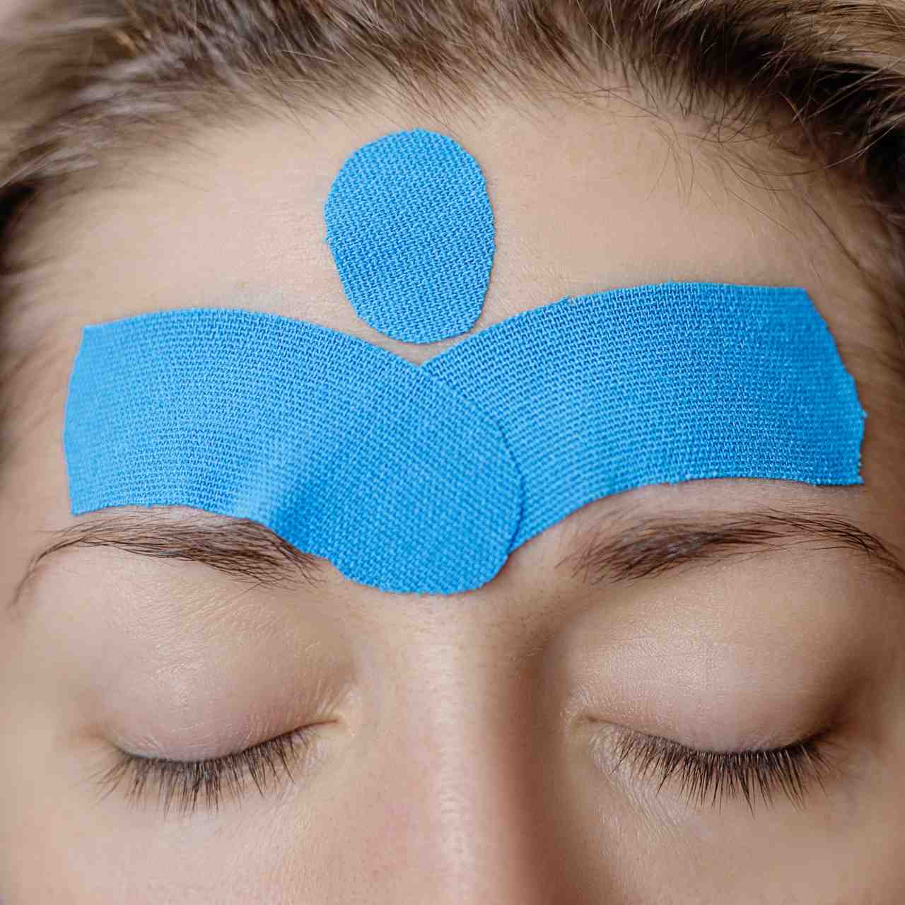 Close-up of forehead with blue medical tape applied