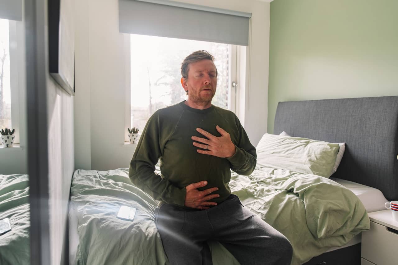 Man sitting on a bed and taking a deep breath
