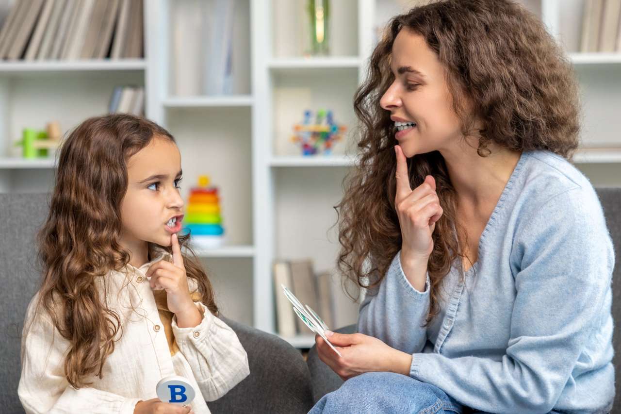 Mother helping daughter with speech therapy at home.