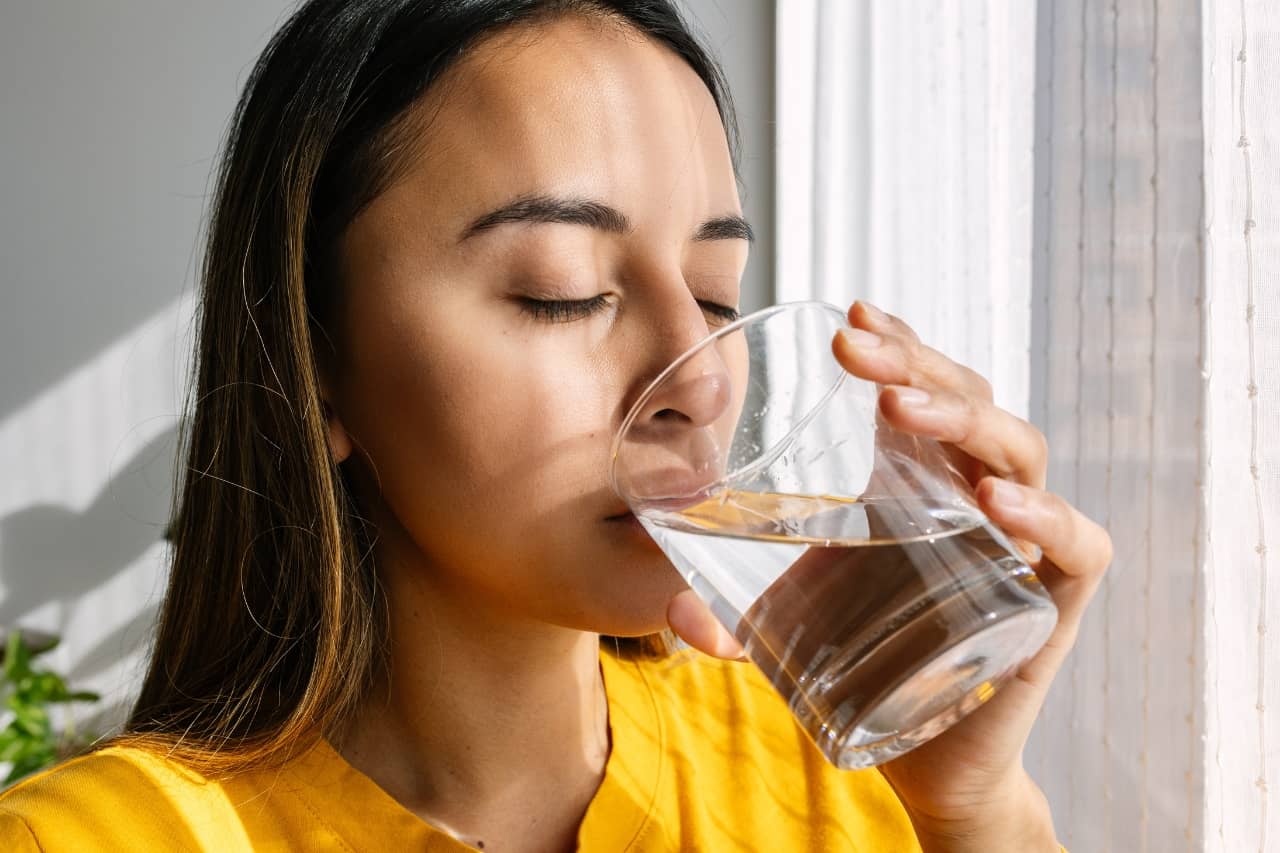Woman drinking from a glass cup of water