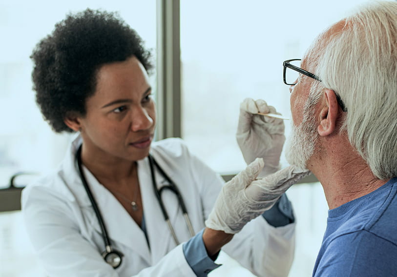 Doctor with tongue depressor on patient