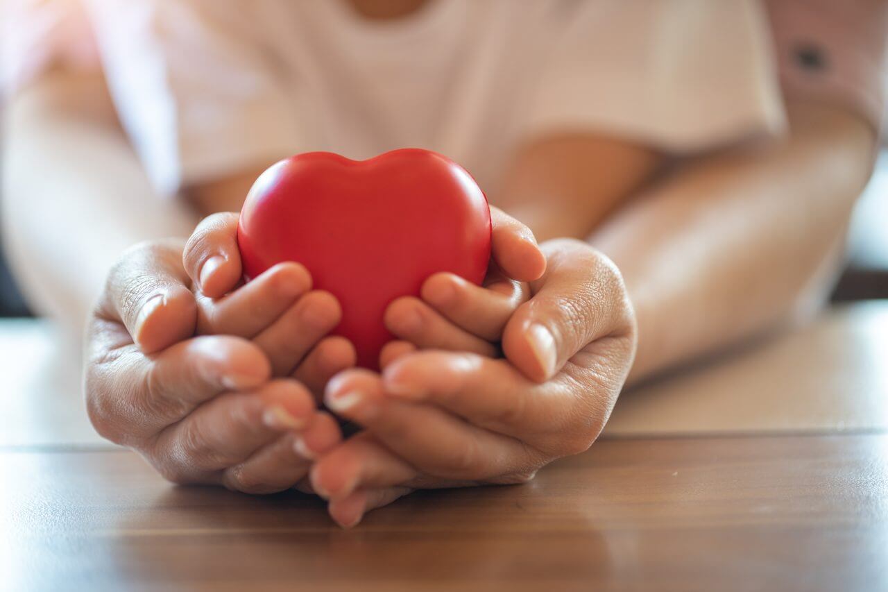 Parent holding kids hands while holding a toy heart
