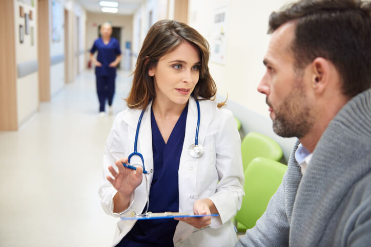 Woman doctor speaking to a man in a hospital hallway