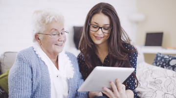 two women looking at a tablet smiling